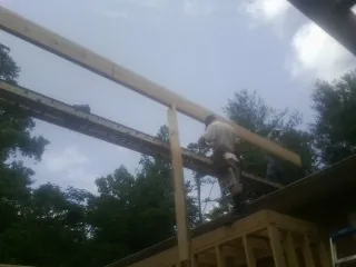 Carpenter setting a ridge beam over a new addition frame — Ice Dam Removal by Roofing Brothers in Daisetta