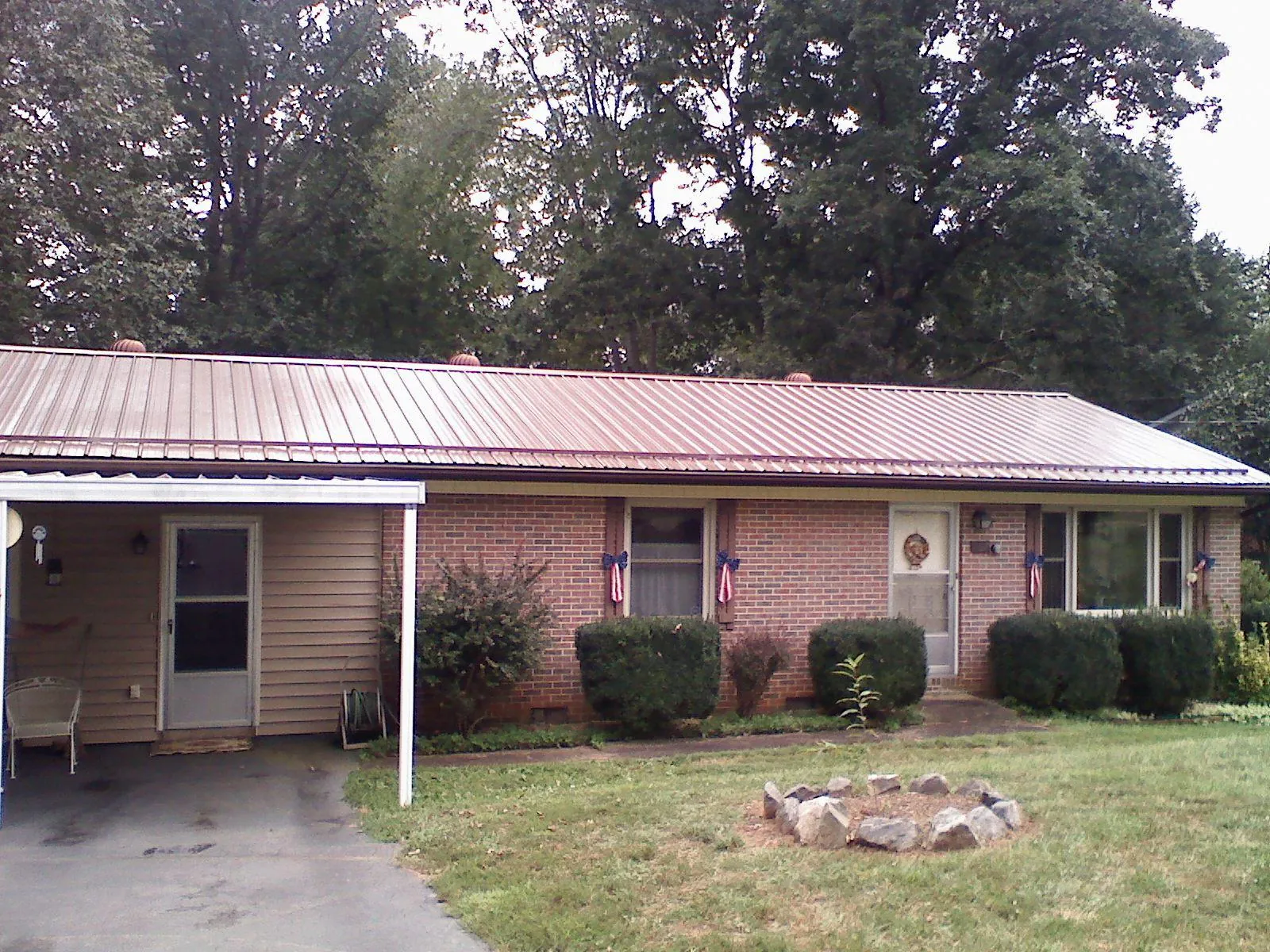 Bronze metal roof and carport on a brick ranch home — Roof Repair work by our crew in Daisetta