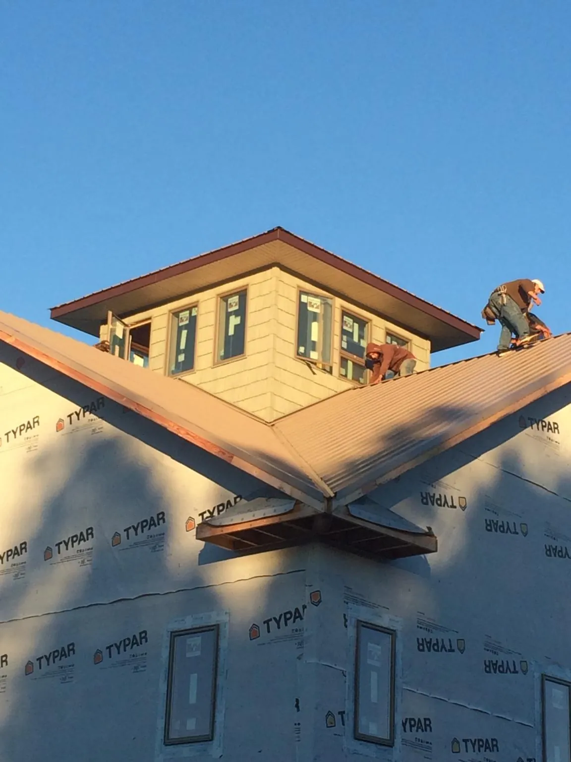 Roofers working around a rooftop cupola on a new metal roof at sunset — Roof Waterproofing in Daisetta by Roofing Brothers